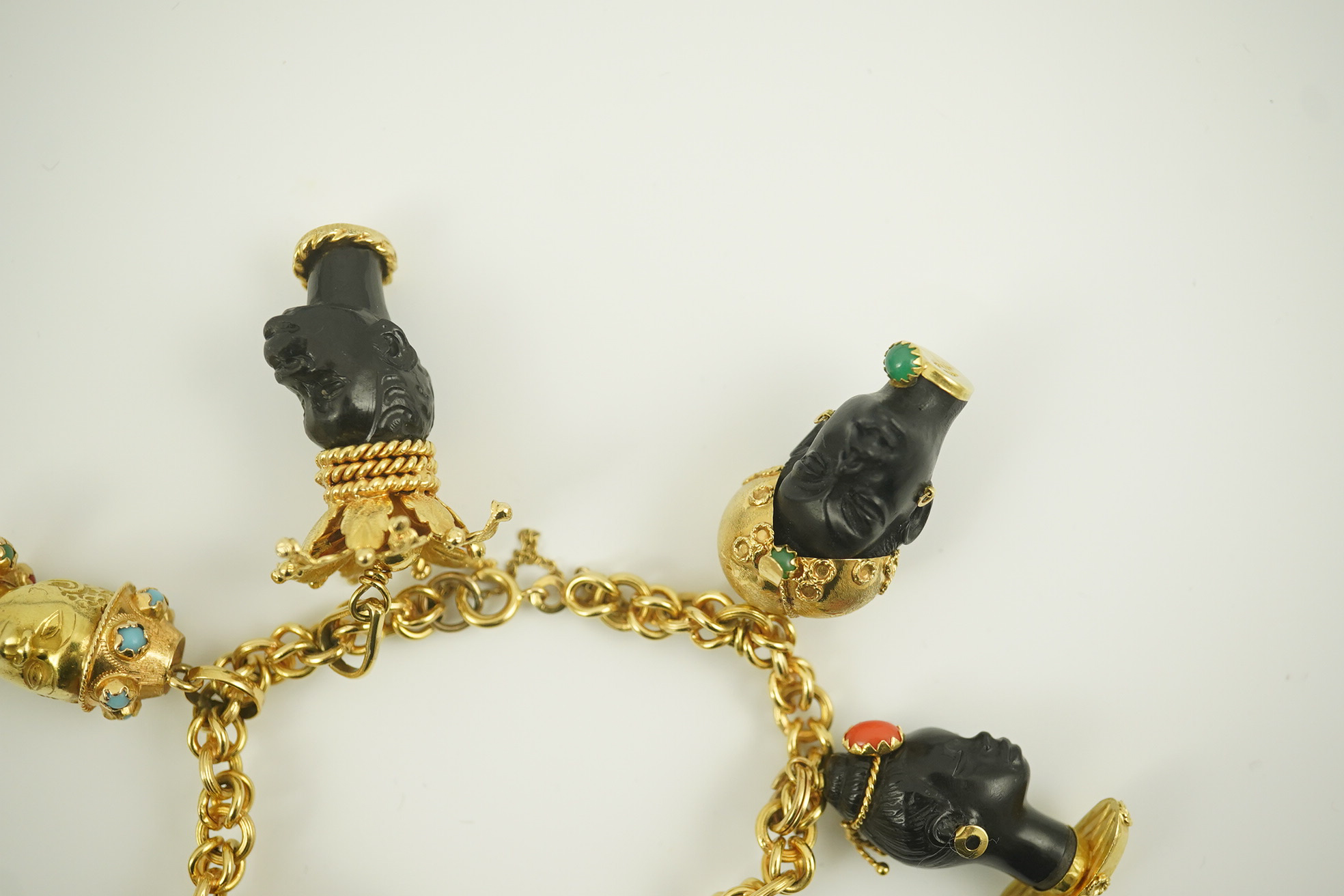 A late 20th century Italian 18k gold charm bracelet, hung with six assorted Italian 18k gold and gem set mounted blackamoor busts, together with a matching brooch